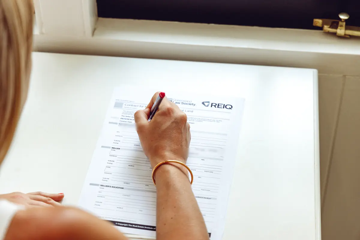 Signing a Queensland property contract with a red pen